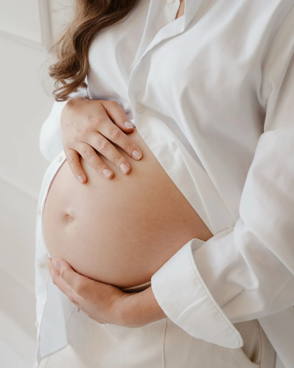 Gravid kvinde med hænderne om maven — graviditet og amning er blandt de tilstande, hvor botox ikke anvendes
